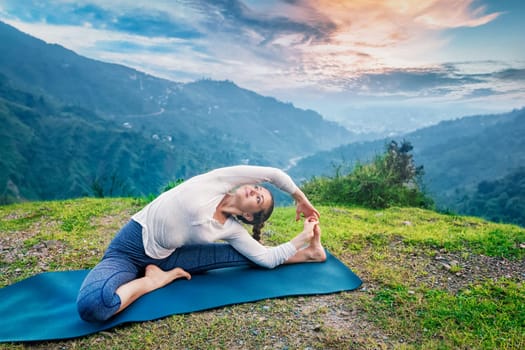 Yoga outdoors - young sporty fit woman doing Hatha Yoga asana parivritta janu sirsasana - Revolved Head-to-Knee Pose - in
