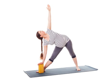 Pregnancy yoga exercise - pregnant woman doing asana Utthita trikonasana - extended triangle pose with block isolated on white background