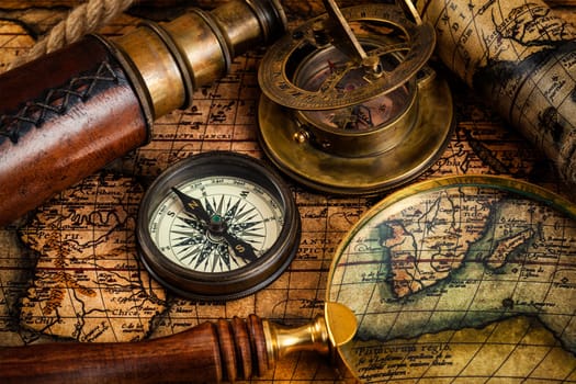 Travel geography navigation concept background - old vintage retro compass, sundial, magnifying glass and spyglass on ancient world map