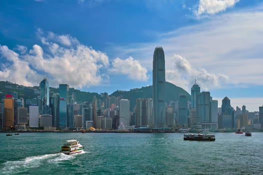 HONG KONG, CHINA - MAY 1, 2018: Boat in Victoria Harbour and Hong Kong skyline cityscape downtown skyscrapers over in the day time with clouds. Hong Kong, China.