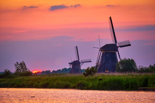 Netherlands rural lanscape with windmills at famous tourist site Kinderdijk in Holland on sunset with dramatic sky