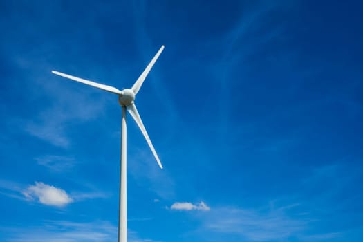 Green renewable alternative energy concept - wind generator turbines generating electricity in blue sky