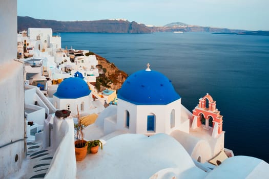 Famous view from viewpoint of Santorini Oia village with blue dome of whitewashed greek orthodox Christian church of traditional greek architecture. Oia town, Santorini island, Greece