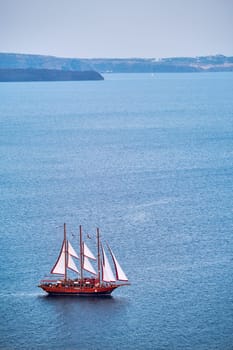 Tourist schooner vessel ship boat in Aegean sea near Santorini island with tourists going to sunset viewpoint. Santorini, Greece