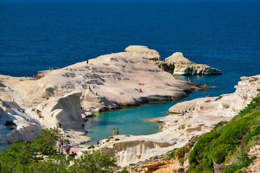 White rocks of famous tourist attraction of Milos island Sarakiniko beach with tourist relax and Aegean sea, Milos island , Greece