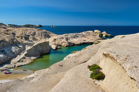 White rocks of famous tourist attraction of Milos island Sarakiniko beach with tourist relax and Aegean sea, Milos island , Greece