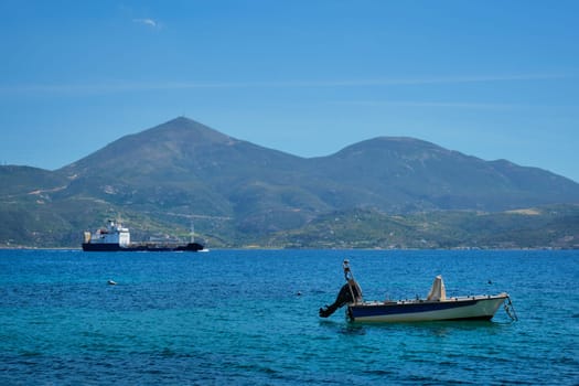 Greek fishing speed boat and cargo ship in the Aegean sea, Milos island, Greece