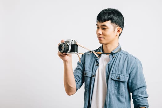 Excited young man smiles as a professional photographer takes his picture with a vintage camera. Studio shot isolated on white background. Glamorous paparazzi moment captured