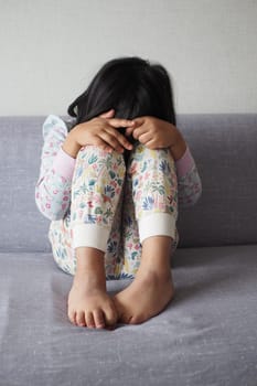 a upset child girl cover her face with hand .