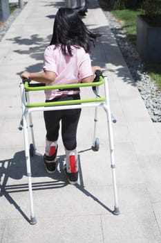 child with walking frame and knee orthosis outdoor .