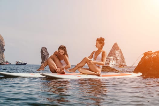 Woman sup yoga. Middle age sporty woman practising yoga pilates on paddle sup surfboard. Female stretching doing workout on sea water. Modern individual hipster outdoor summer sport activity