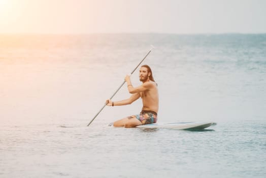 Sea woman and man on sup. Silhouette of happy young woman and man, surfing on SUP board, confident paddling through water surface. Idyllic sunset. Active lifestyle at sea or river