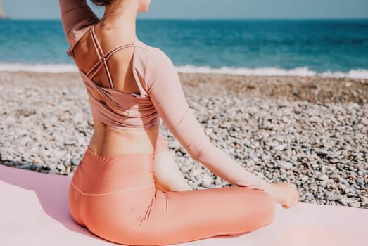 Middle aged well looking woman with black hair doing Pilates with the ring on the yoga mat near the sea on the pebble beach. Female fitness yoga concept. Healthy lifestyle, harmony and meditation.