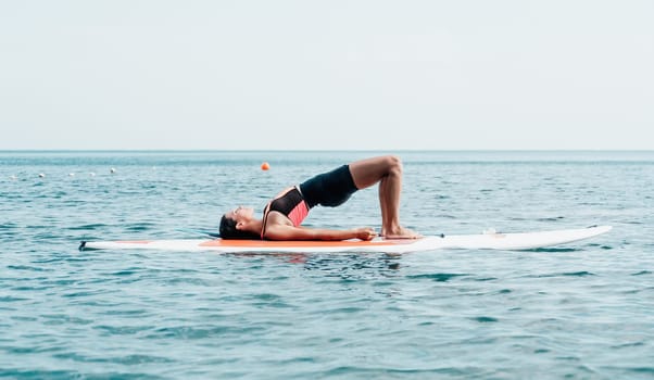 Woman sup yoga. Happy young sporty woman practising yoga pilates on paddle sup surfboard. Female stretching doing workout on sea water. Modern individual female outdoor summer sport activity