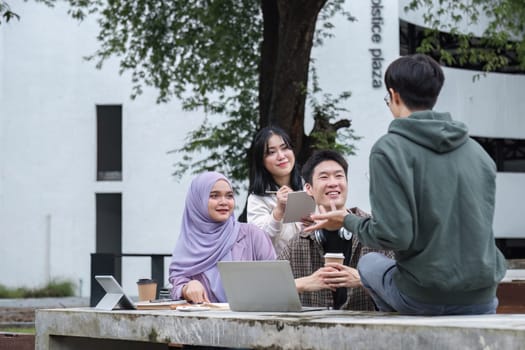 A multiracial group of students at the college, including Muslim and Asian students, sat on benches in a campus break area. Read books or study for exams together..