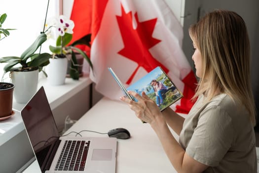 female student sitting with canadian flag and using laptop . High quality photo