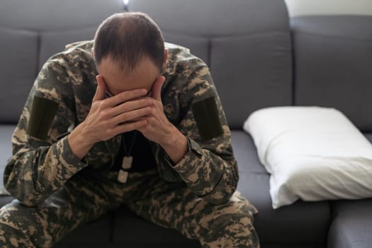 Nervous male military suffering depression, sitting alone at home, PTSD concept. High quality photo