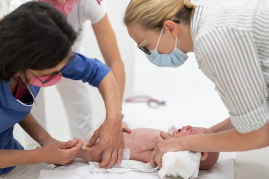 Baby beeing vaccinated by pediatrician in presence of his mother. Preventive vaccination against Diphtheria, whooping cough, tetanus, hepatitis, haemophilus influenzae, pneumococcus, poliomyelitis.