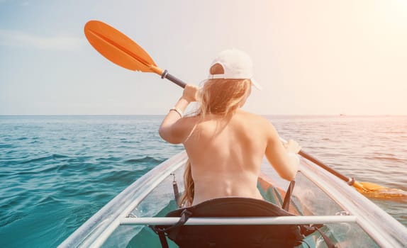 Woman in kayak back view. Happy young woman with long hair floating in transparent kayak on the crystal clear sea. Summer holiday vacation and cheerful female people having fun on the boat.