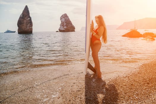 Close up shot of beautiful young caucasian woman with black hair and freckles looking at camera and smiling. Cute woman portrait in a pink bikini posing on a volcanic rock high above the sea