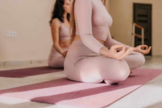 Young woman with long hair in white swimsuit and boho style braclets practicing outdoors on yoga mat by the sea on a sunset. Women's yoga fitness routine. Healthy lifestyle, harmony and meditation