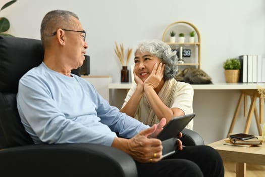 Loving senior couple having a conversation together while relaxing at home. Elderly lifestyle and marriage concept.