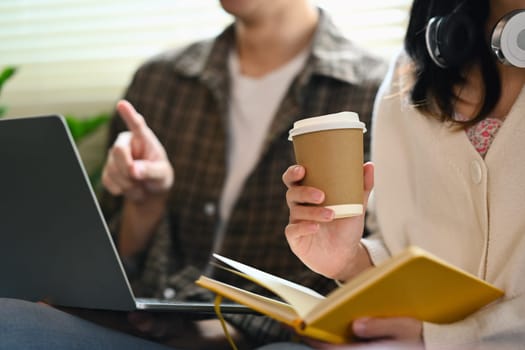 University students using laptop for researching online, collaborating on a project in campus.