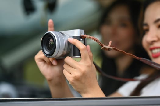 Smiling young woman tourist taking photos with vintage retro camera during road trip.