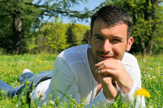 An attractive and cheerful man lying in the park