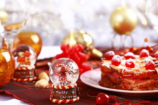 Christmas table setting with Charlotte cake with small snow globe