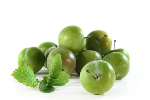 green mirabelle plums against white background