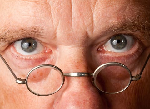 Portrait of a senior male with the focus on magnifying glasses and the eyes are in focus