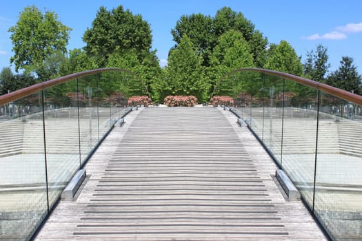 a pedestrian bridge over a river in a city in bloom