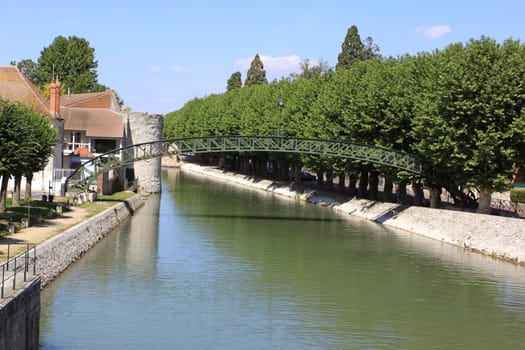 a river with its bridge rainbow sky surrounded by trees in the town of Montargis
