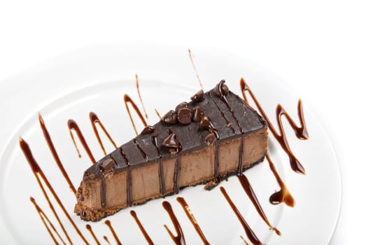 chocolate cake on a white plate drizzled with chocolate sauce on a white