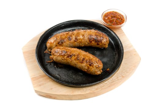 Roasted sausages at pan with sauce on a white background