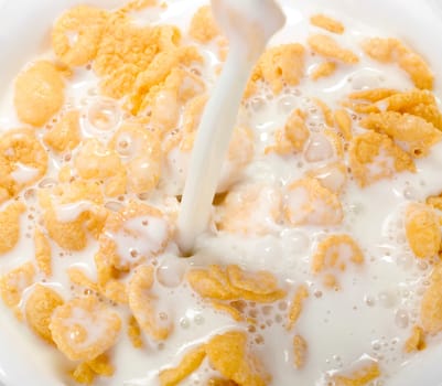 Milk pouring in a bowl of cornflakes closeup