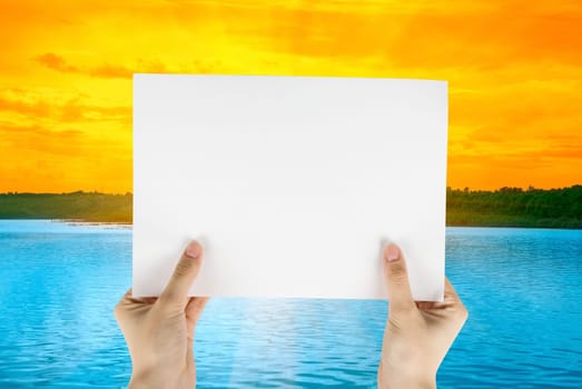 Hand holding white paper at beauty sunset on river background
