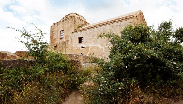 dis-used church in Cappadocia, limestone built with a small dome, over grown hedges and gardens, landscape, copy space and crop space