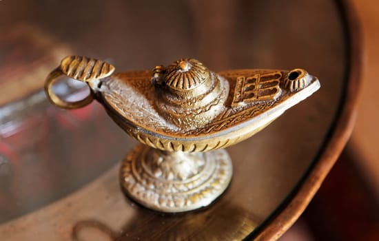ornate brass lamp with handle on a round occasional table. Landscape, crop space and copy area.