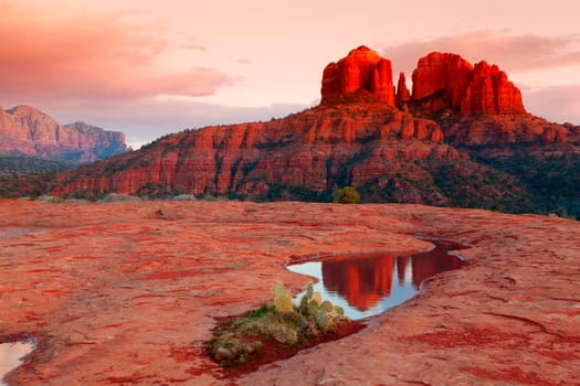 Cathedral Rock in the distance is reflected in a pool of water at sunset