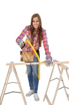 Young woman with a hacksaw sawing a board