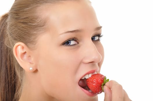 Young woman with blue eyes biting into a strawberry