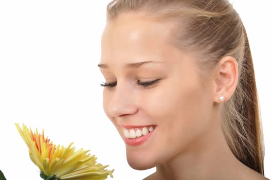 Attractive young woman smelling a yellow flower