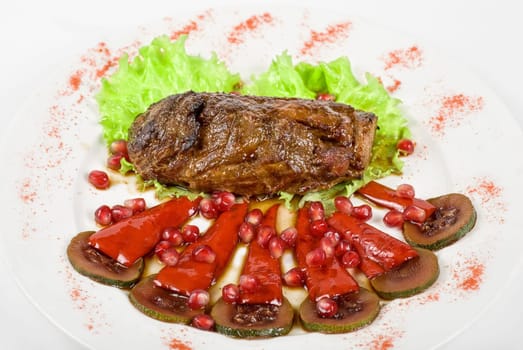 Roasted beef steak with pomegranate closeup at plate