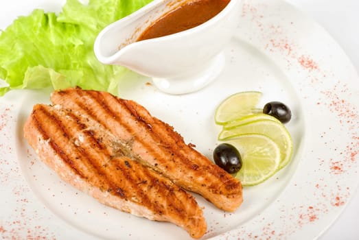 Grilled trout steak with sauce,greens, lemon and olive