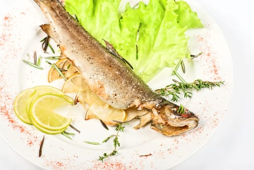 fish with lemon and greens on white background