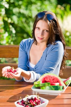 Beautiful young woman fresh summer melon cherries sitting garden terrace