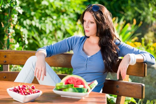 Beautiful young woman fresh summer fruit sitting on garden terrace