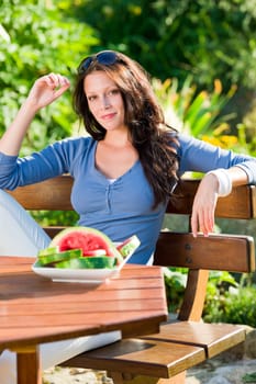 Beautiful young woman fresh melon summer sitting on garden terrace
